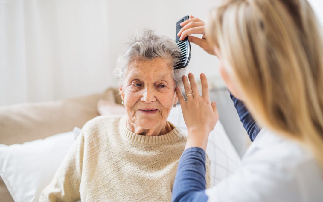 young woman combing elderly woman's hair
